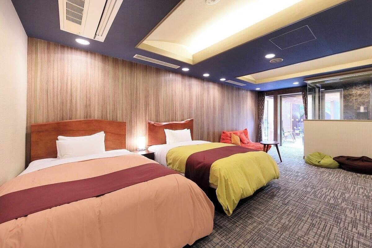 A hotel room with two beds, a wooden headboard, a large window, and a carpeted floor.