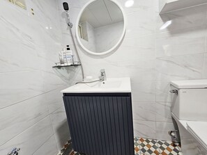 Bathroom features a pedestal sink, toilet, and handheld showerhead.