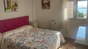 Ein Schlafzimmer mit Bett, Heizkörper, Klimaanlage, Fenster mit Blick und einem Gemälde an der Wand.