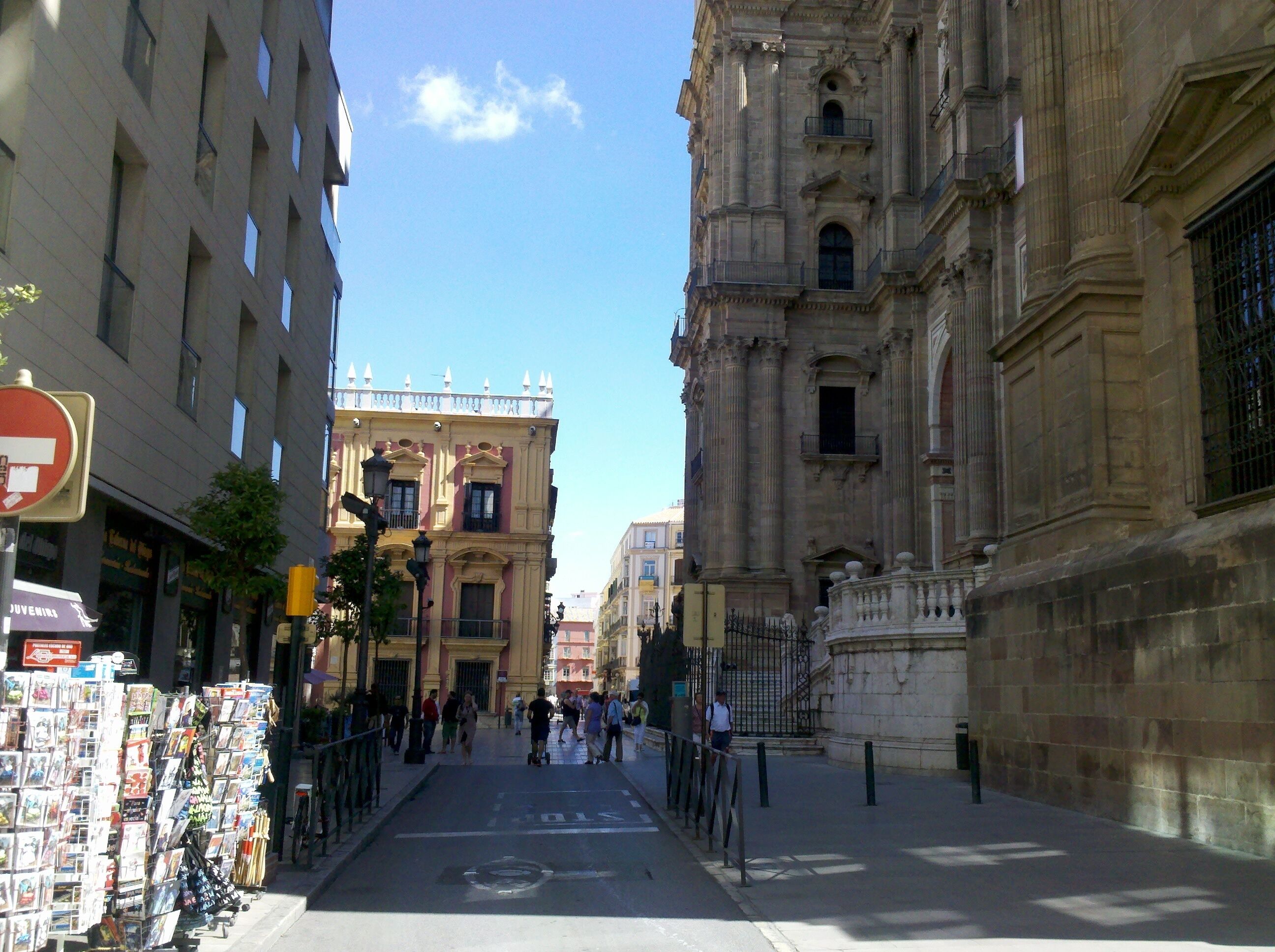A street with a row of shops on the left and a historic building on the right.