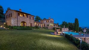 Une villa en pierre dotée d’une piscine et d’espaces extérieurs bien éclairés.