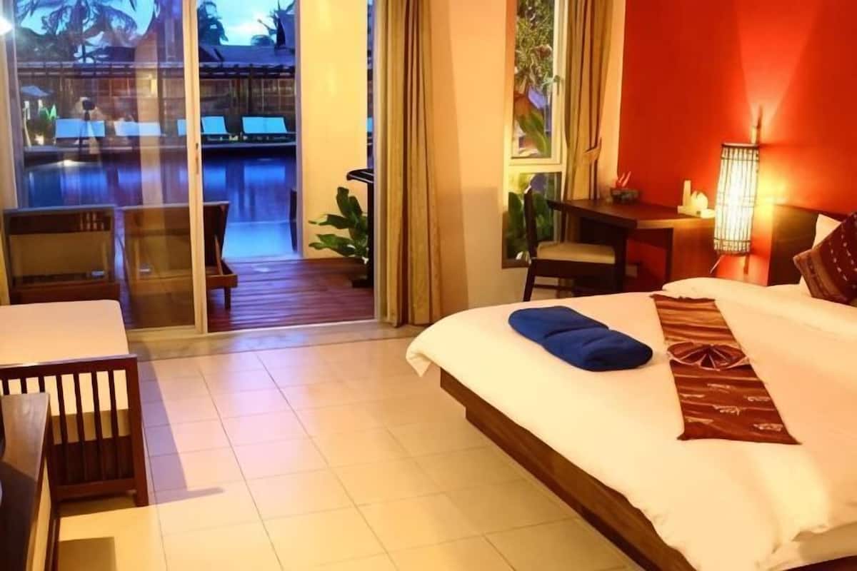 Une chambre d’hôtel comprenant un lit, un bureau, une chaise, une table et donnant sur une piscine extérieure.