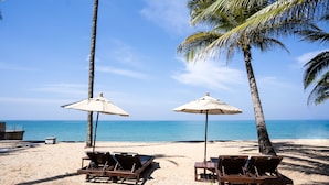 Pantai pribadi, pasir putih, kursi berjemur, dan payung pantai