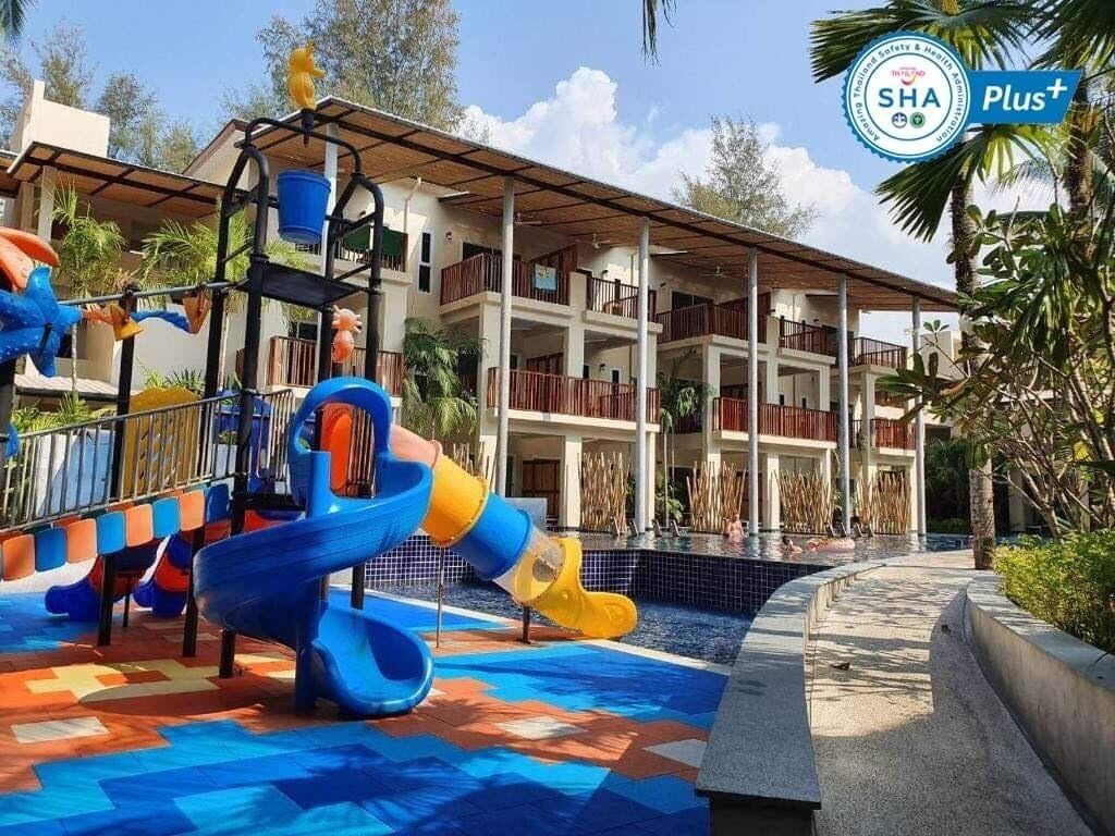 A water park area with multiple slides and a pool, surrounded by a building with balconies.