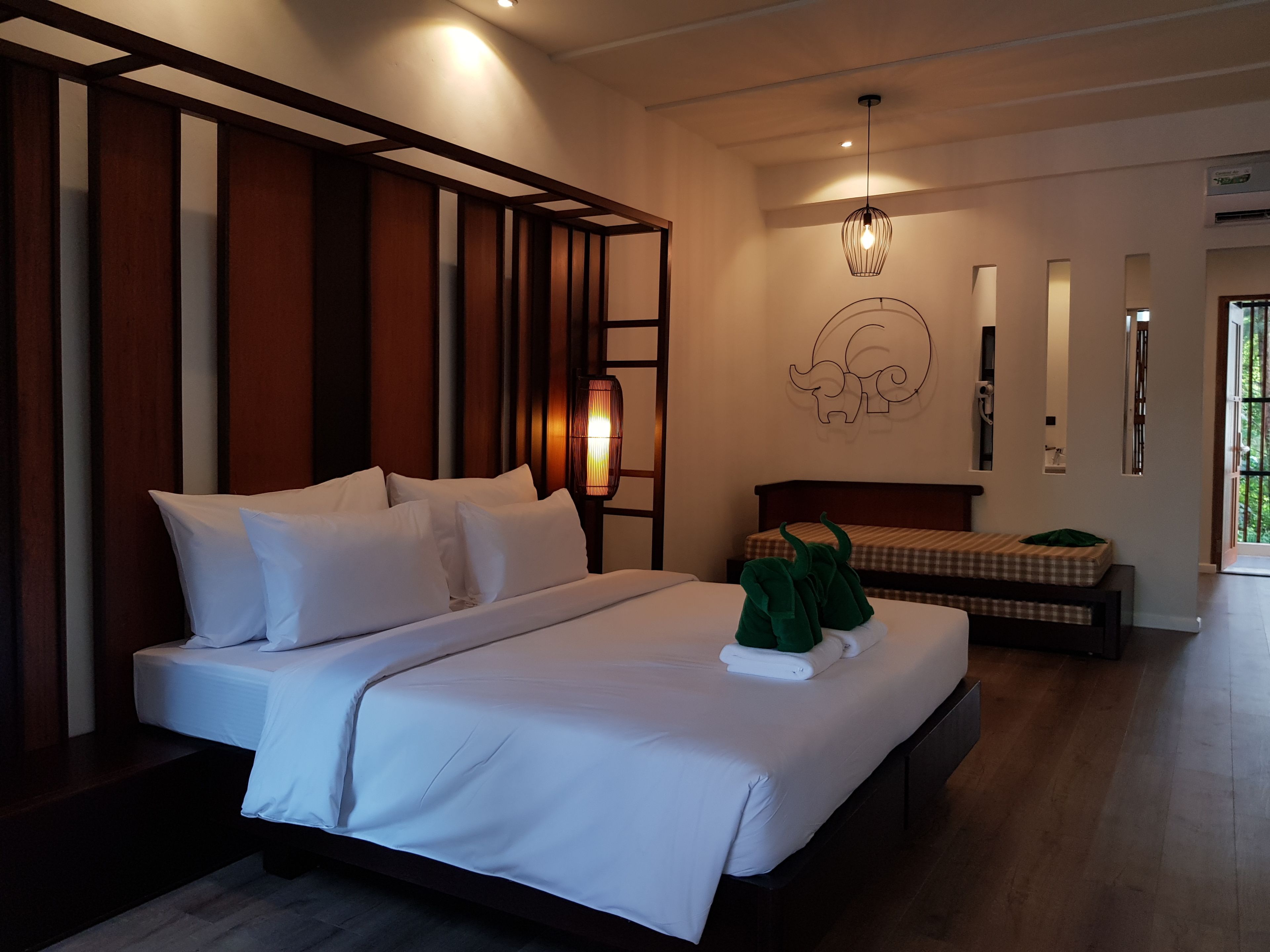 Ett modernt hotellrum med en stor säng, ett sängbord, en lampa och en dekorativ väggdekoration.