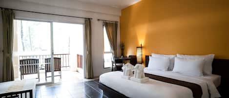 A hotel room with a large bed, a desk, a chair, and a balcony with curtains.