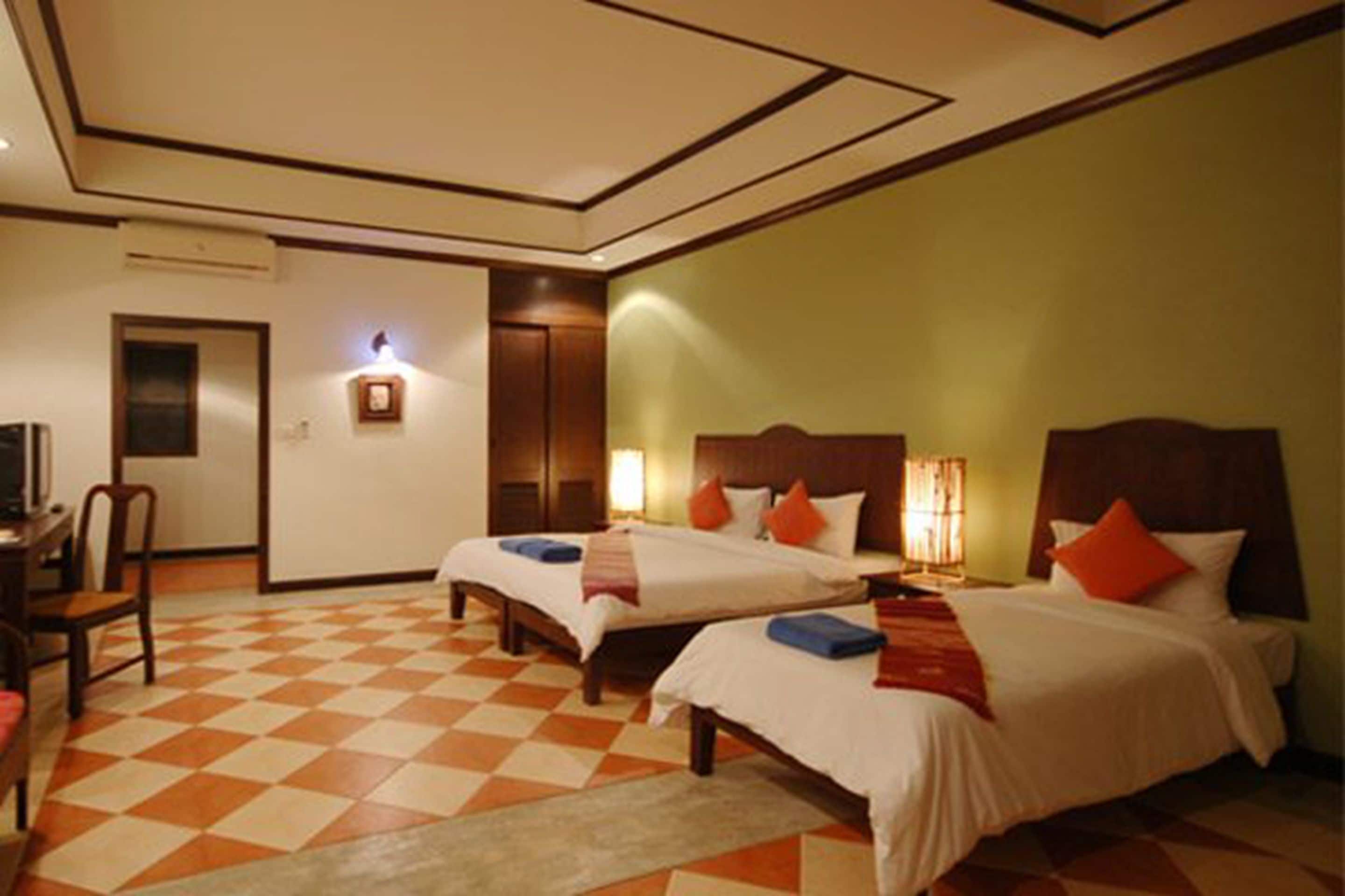 Ein Hotelzimmer mit zwei Betten, einem Schreibtisch und einem Sessel.