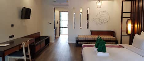 A hotel room with a bed, a desk, a chair, a television, and a wall-mounted air conditioner.