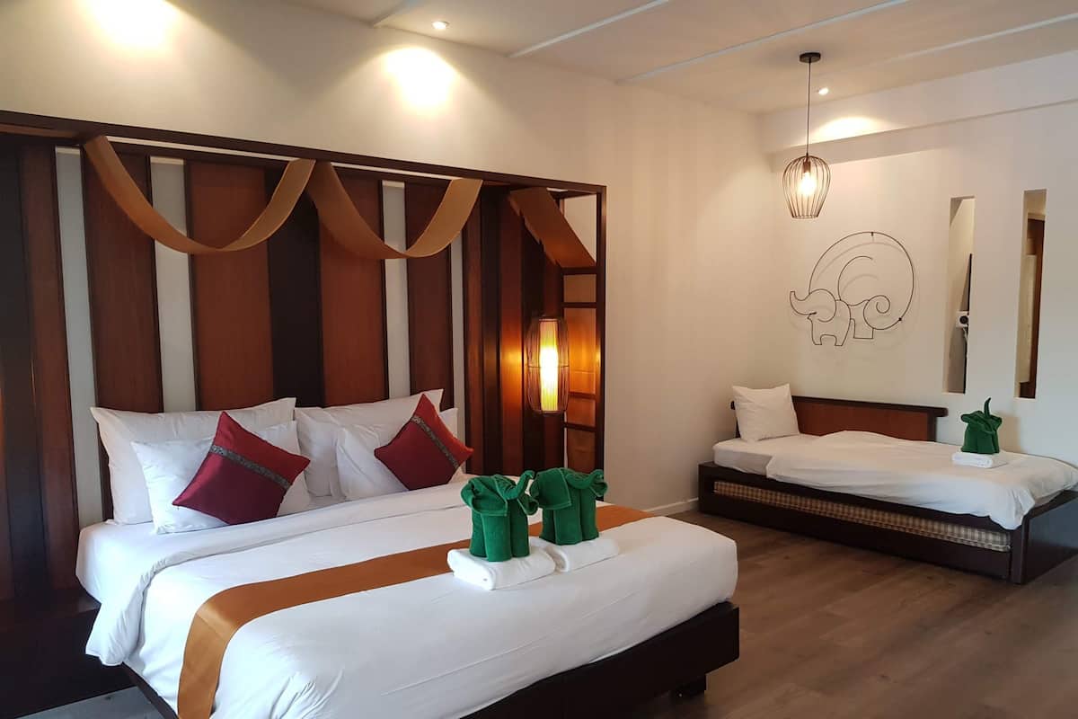 Une chambre d’hôtel avec deux lits, des têtes de lit en bois et un grand miroir.