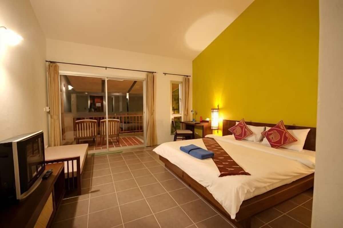 Une chambre d’hôtel avec un lit, un bureau, une chaise, une télévision et un balcon.