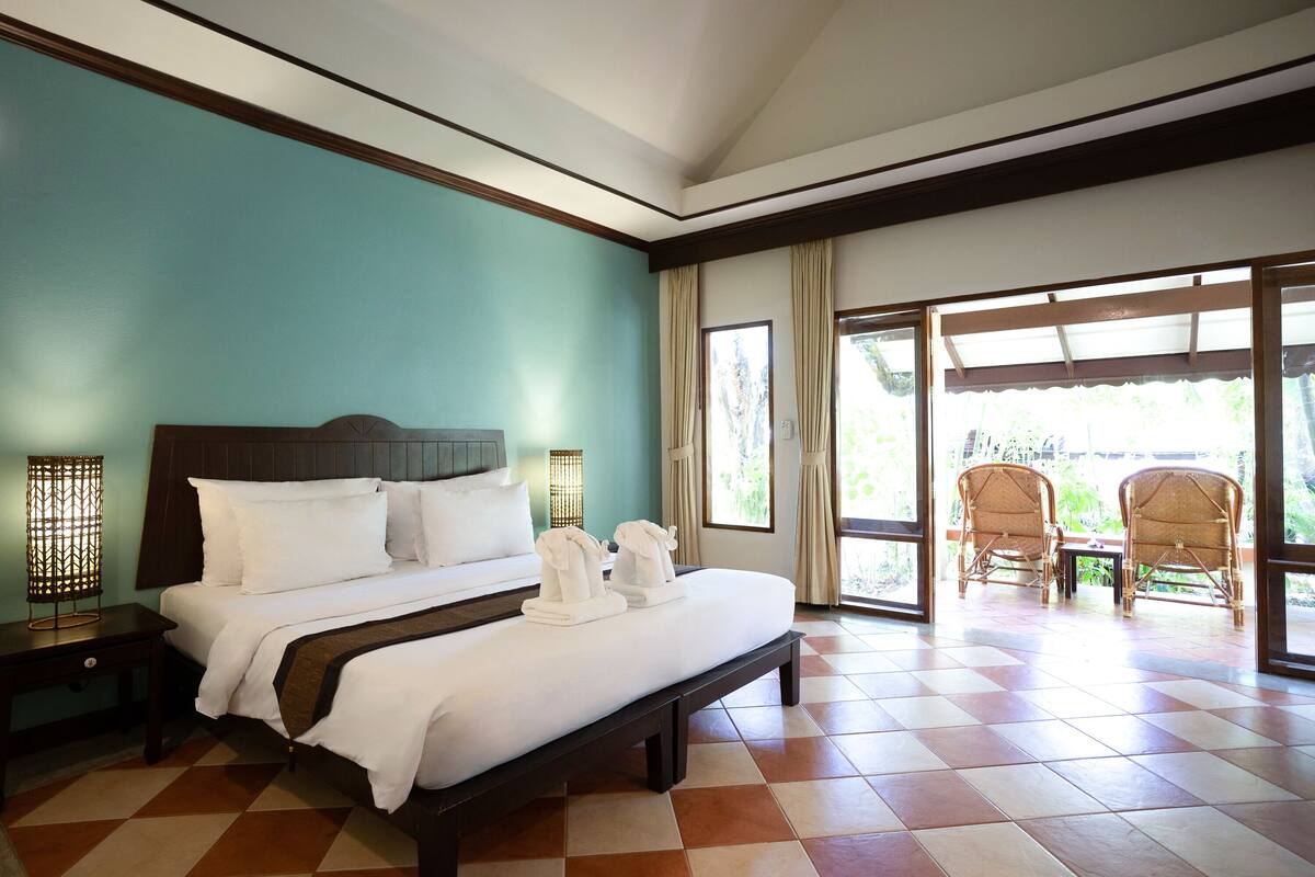 Une chambre d’hôtel comprenant un lit, deux tables de chevet, une table et des chaises.