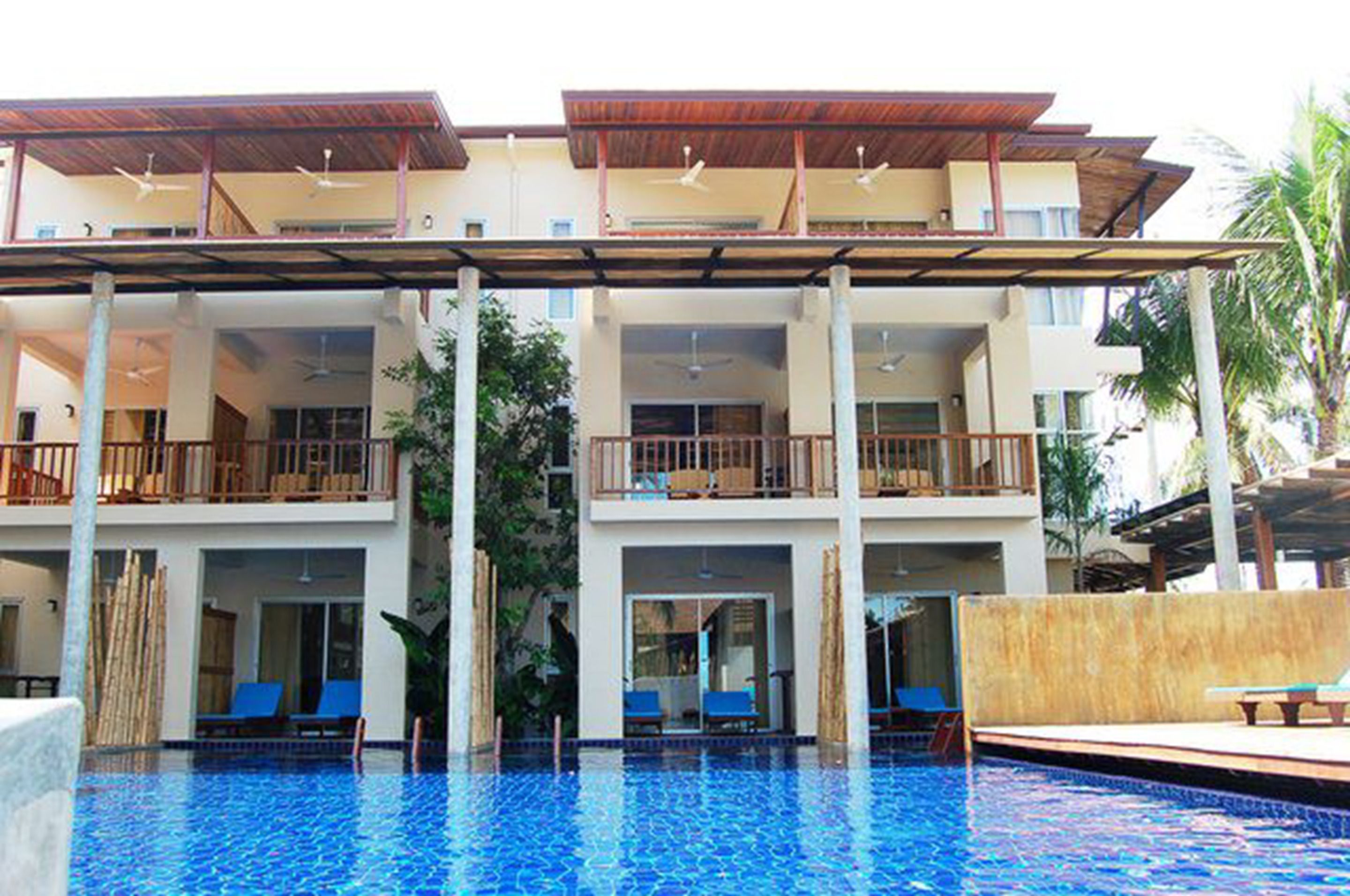 A hotel with a pool, multiple balconies, and a covered outdoor area.