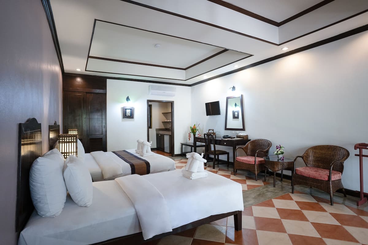 Une chambre d’hôtel avec deux lits, un bureau, une chaise et un téléviseur.