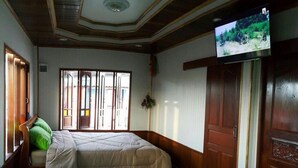 Une chambre d’hôtel avec deux lits, un téléviseur fixé au mur et une fenêtre donnant sur l’extérieur.