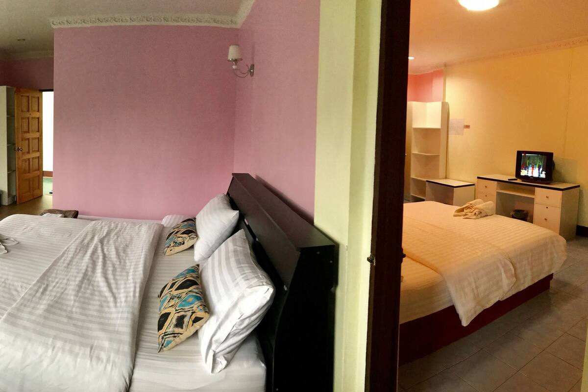 A hotel room with a large bed, a TV, and a desk with a chair.