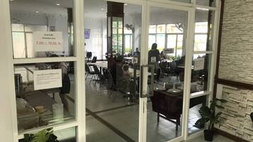 Un restaurant avec une enseigne indiquant les heures du service du petit-déjeuner, des tables, des chaises et un mur en pierre.