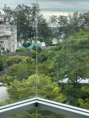 A view from a window overlooking a residential area with trees and a building with a blue roof. - The Great Rayong Hotel (Rayong)