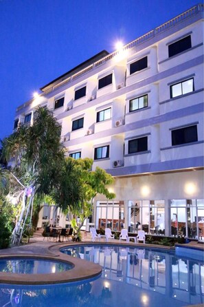 A hotel with a swimming pool, outdoor seating, and a multi-story building with balconies. - The Great Rayong Hotel (Rayong)