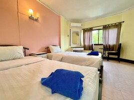 A hotel room with two beds, a desk, a chair, a mirror, and an air conditioning unit.