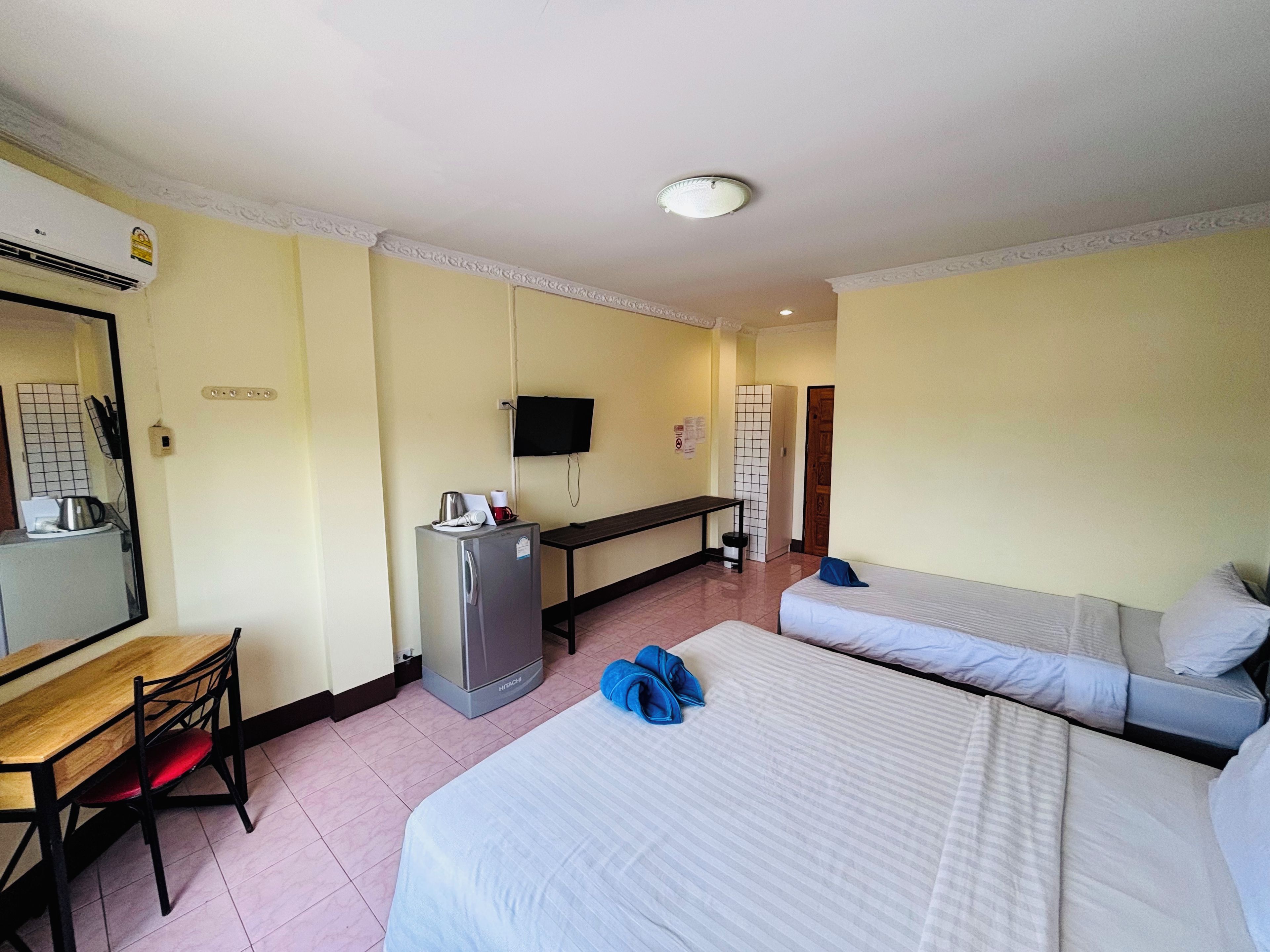 Une chambre d’hôtel avec deux lits, un bureau, un réfrigérateur, une télévision et un miroir.