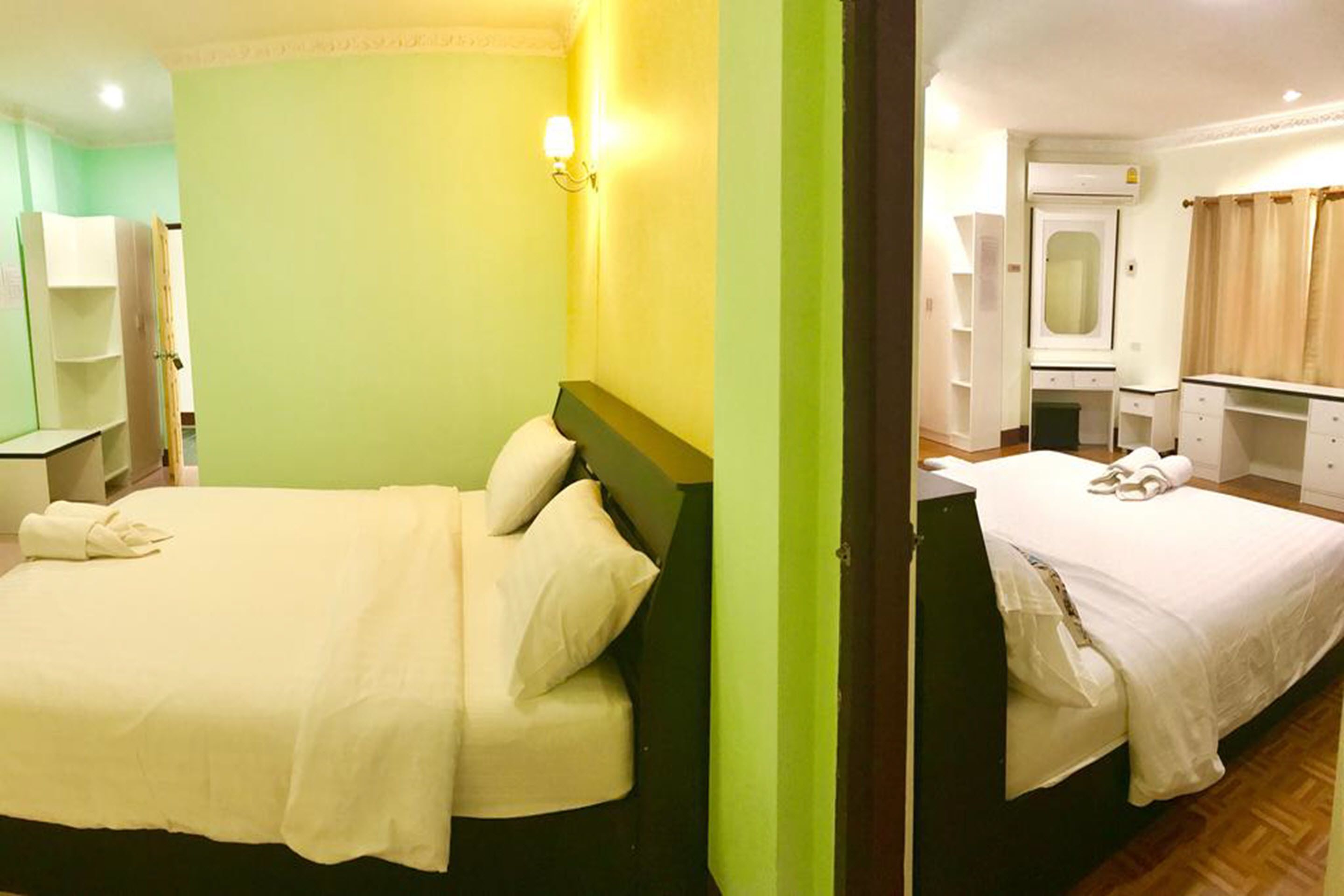 Et hotelværelse med to senge, et lille skrivebord, et spejl og en garderobe.