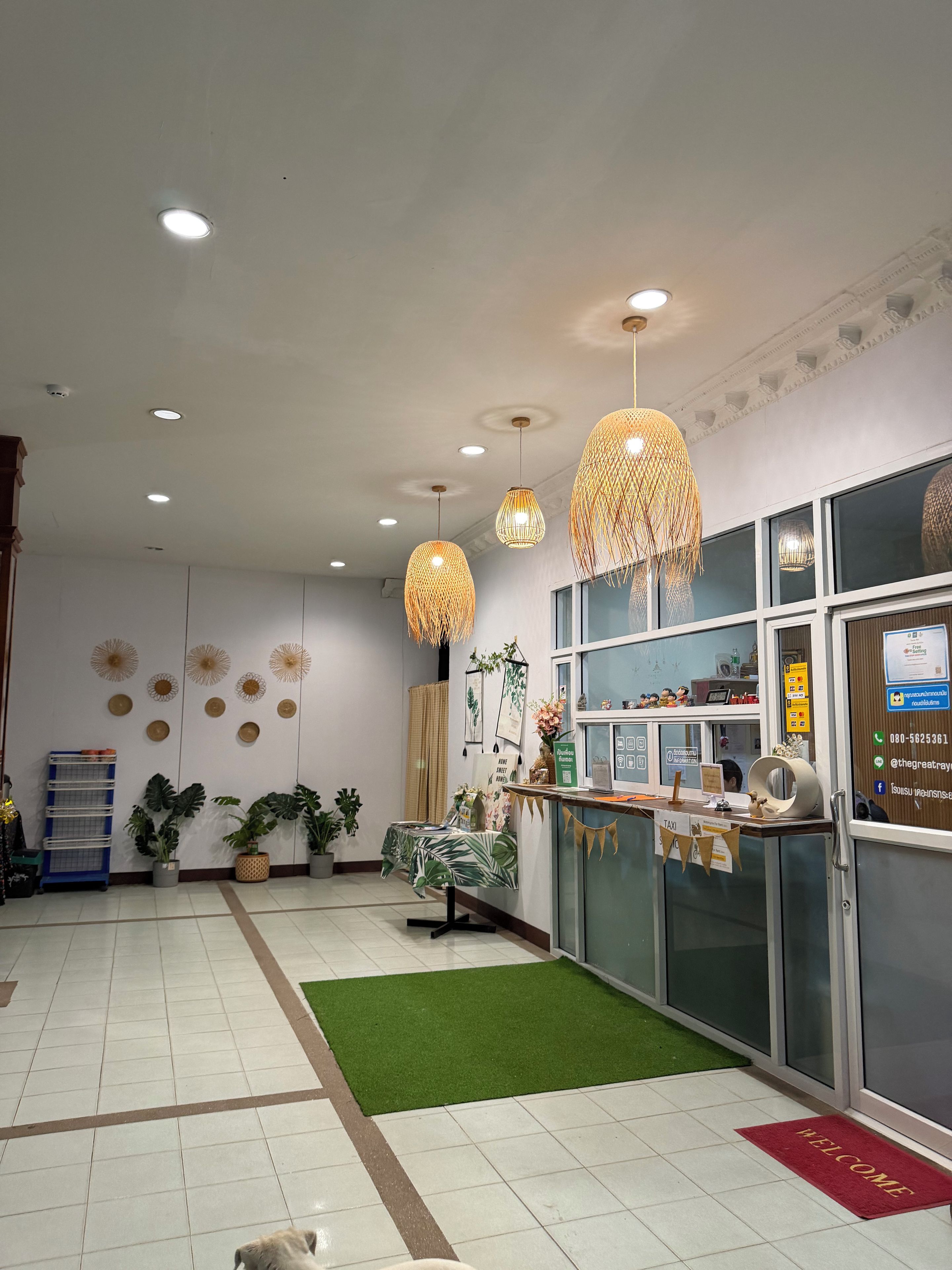 Un área de recepción con mostrador, un felpudo verde y una alfombra de bienvenida.