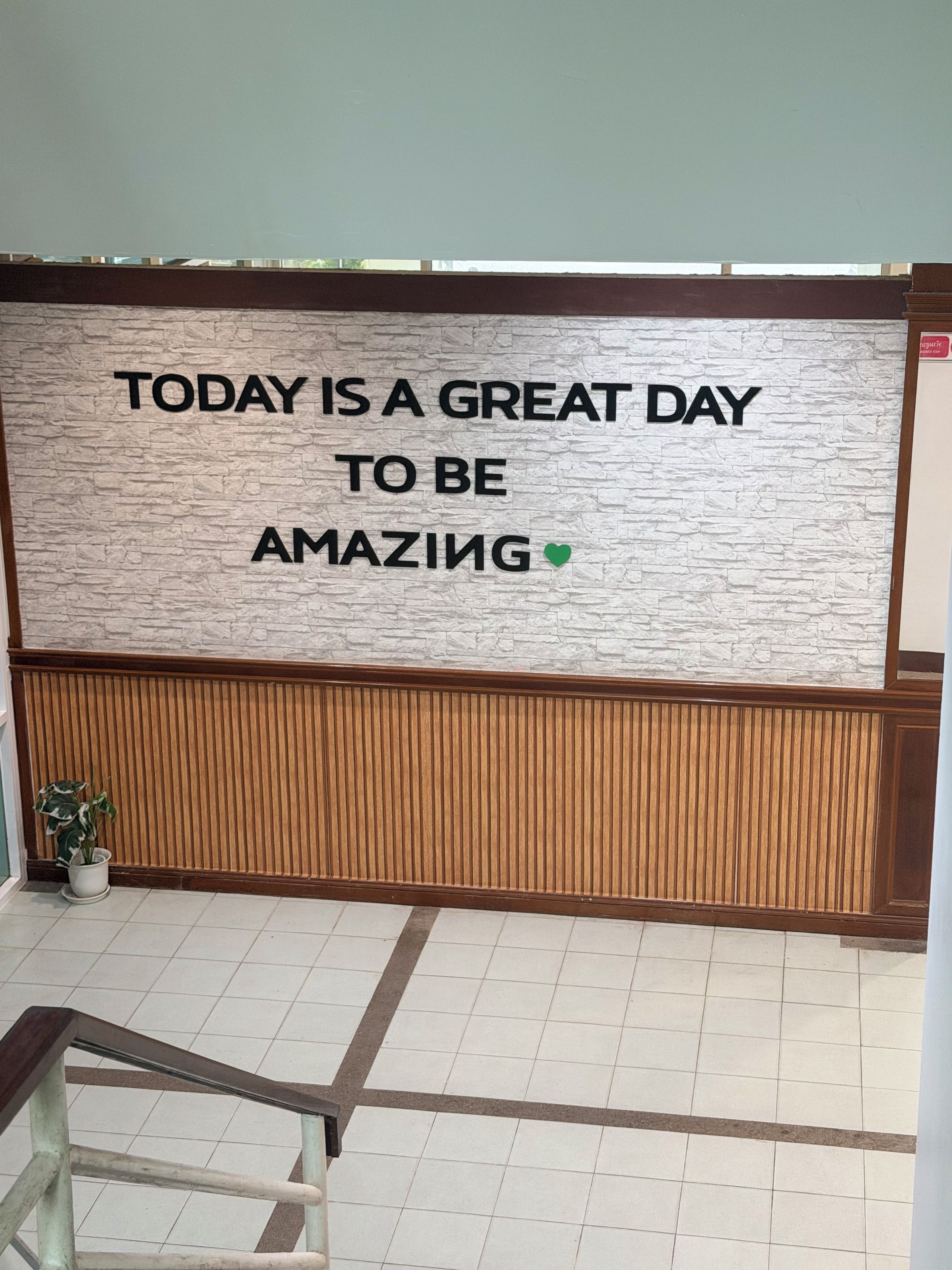 A wall with a motivational quote and a wooden panel below it.