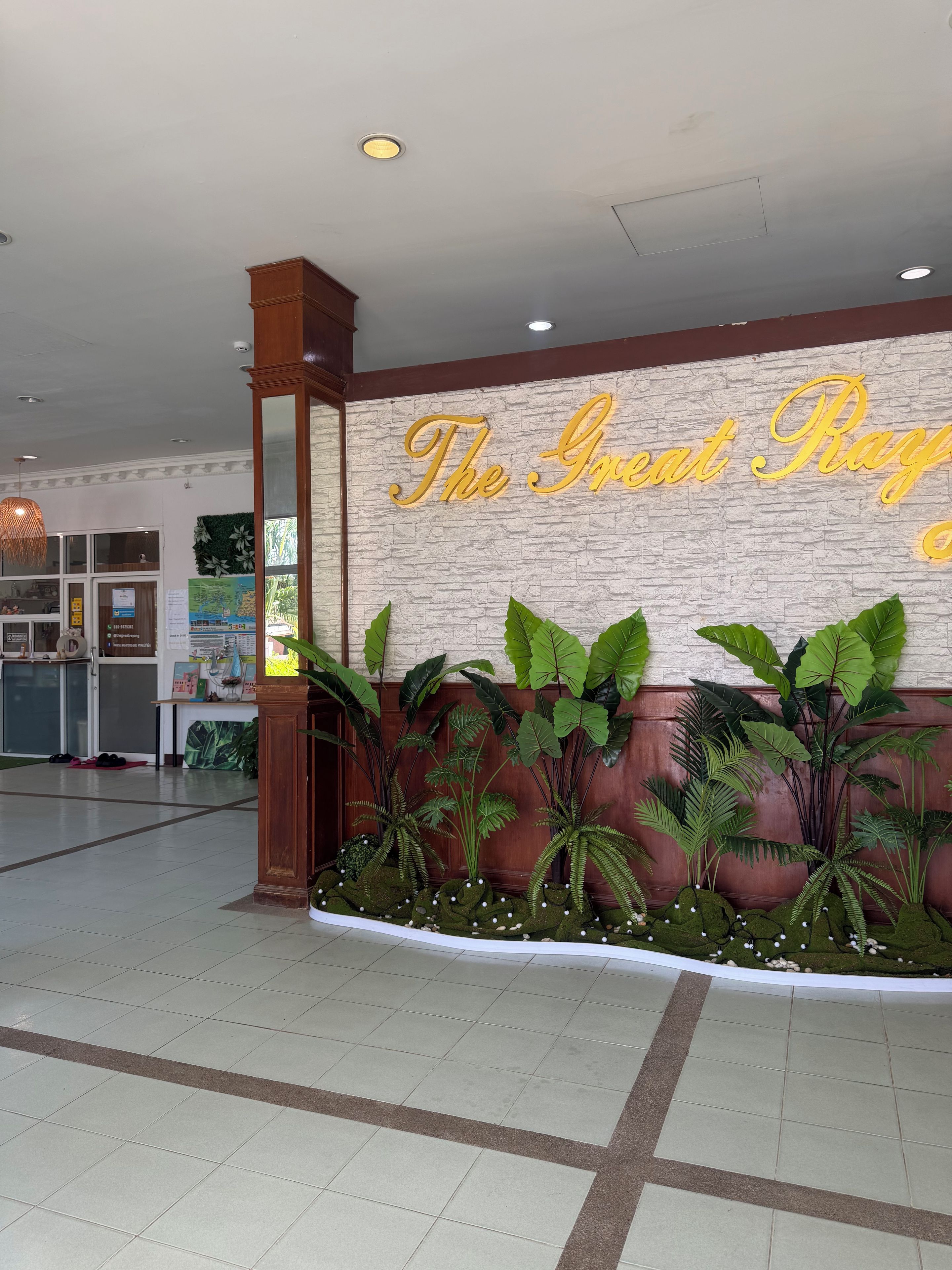 A reception area with a wall sign, indoor plants, and a tiled floor.