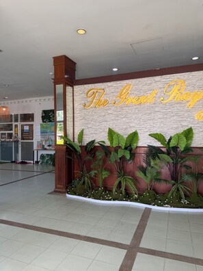 A reception area with a wall sign, indoor plants, and a tiled floor. - The Great Rayong Hotel (Rayong)