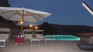 Un espace aménagé au bord de la piscine, avec des chaises longues et un parasol.