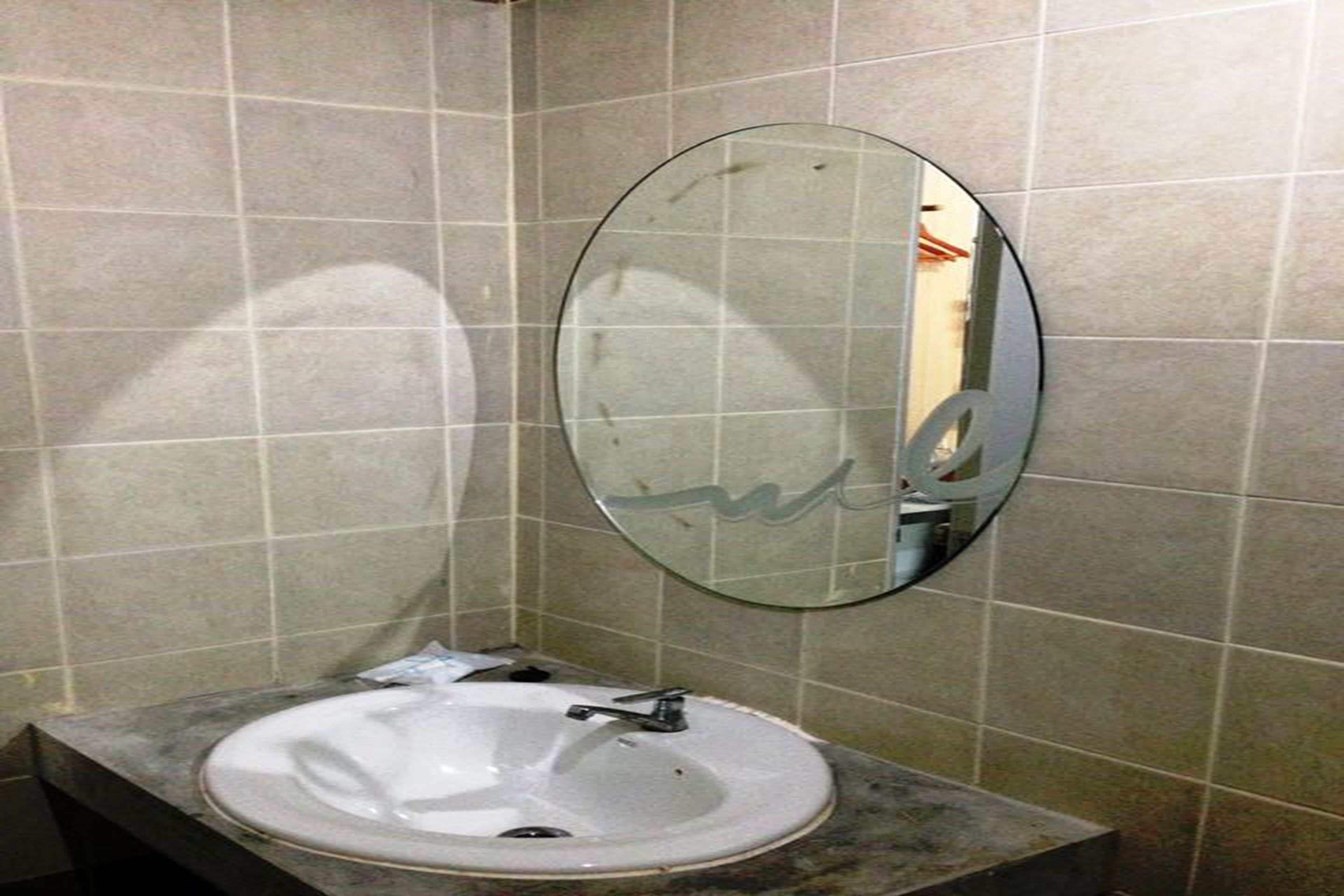 A bathroom with a white sink, a mirror, and tiled walls.