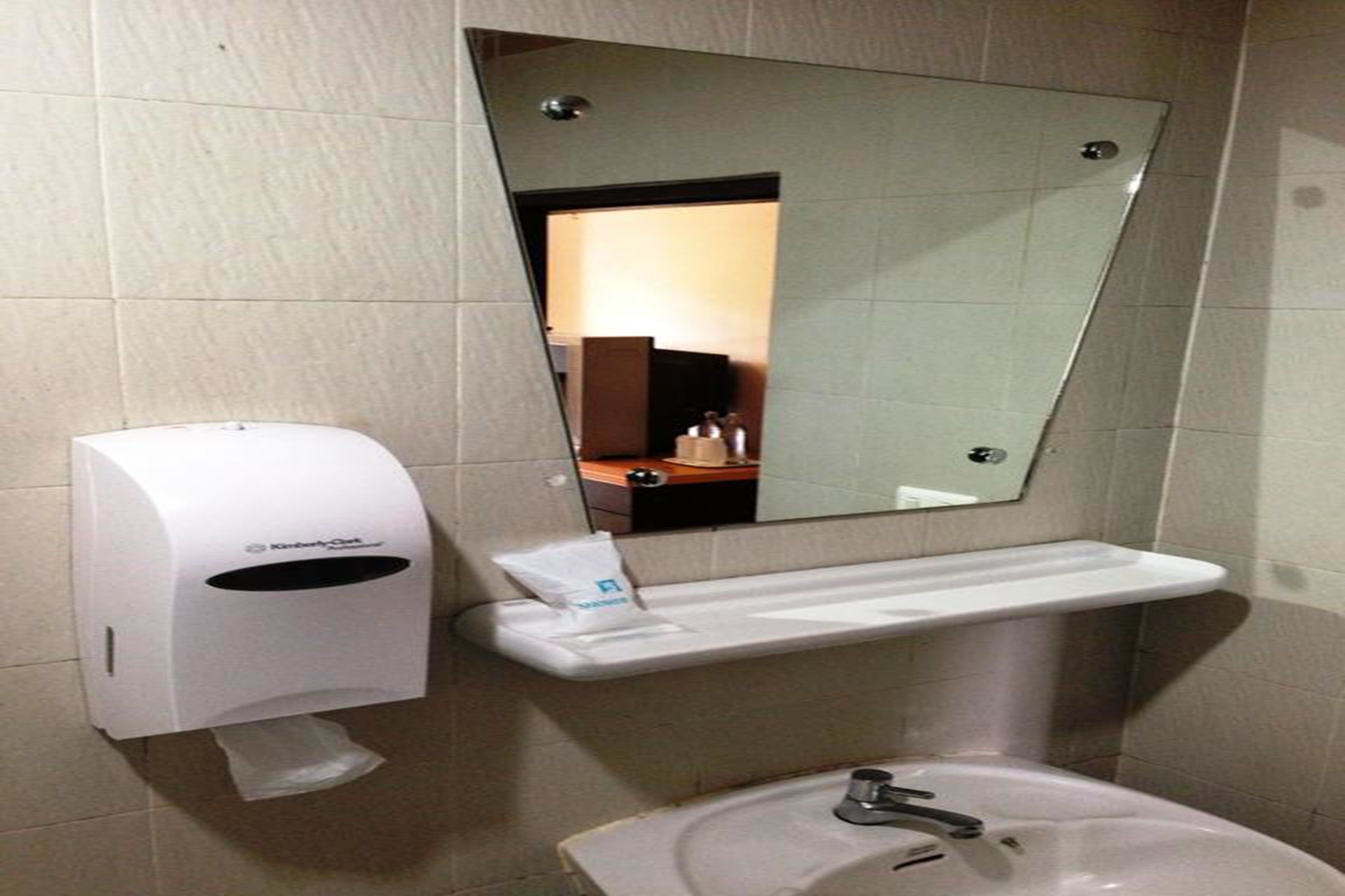A restroom with a hand dryer, a sink, and a mirror.