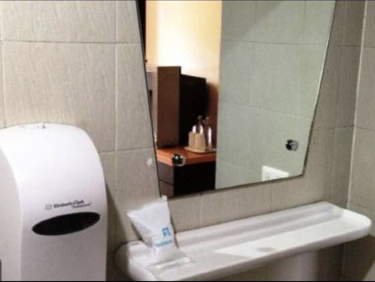 Baño con secador de manos, dispensador de pañuelos de papel y espejo.