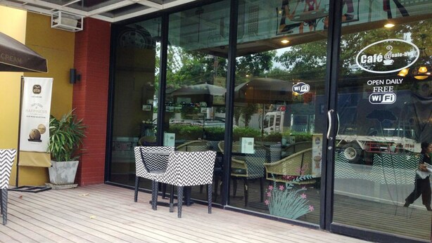 A cafe with outdoor seating, a glass storefront, and a sign indicating free Wi-Fi. - PK Mansion (Wichit)