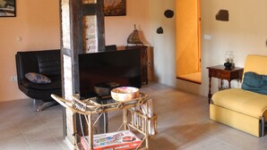 A living room with a fireplace, a sofa, a yellow armchair, and a table with a bowl. - Spacious, original, cozy, flooded with light, fiberglass, autonomous (Torroja del Priorat)
