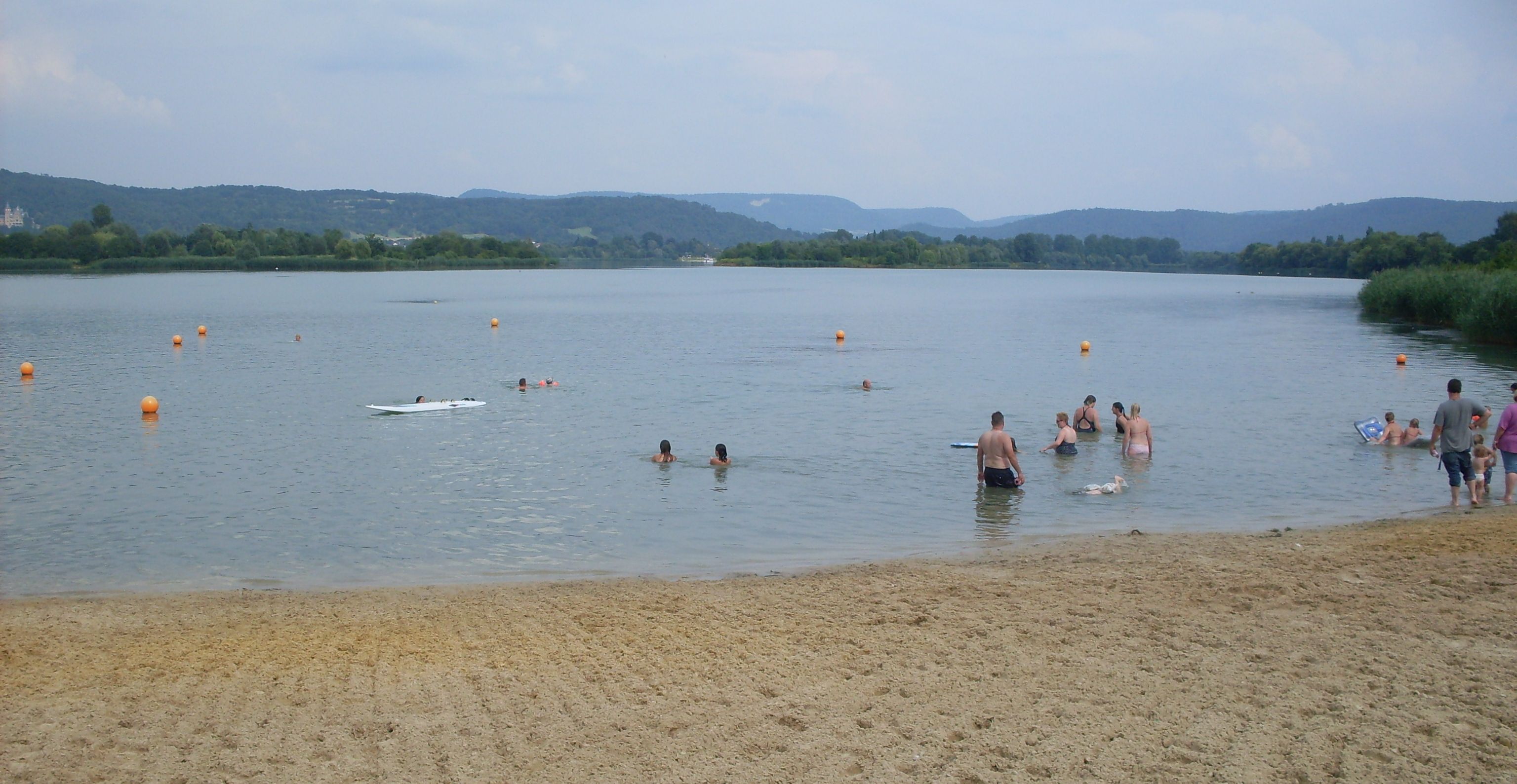 Una spiaggia sabbiosa con persone che nuotano e si godono il mare.