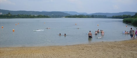 Una spiaggia sabbiosa con persone che nuotano e si godono il mare.