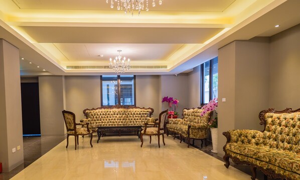 A spacious living room with a high ceiling, ornate furniture, and a chandelier.