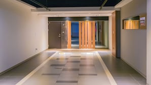 A modern hotel corridor with a check-in desk, a reception area, and a blue door leading to rooms. - Wei Feng Motel (Kaohsiung)