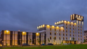 A modern hotel with multiple floors, a prominent sign, and a parking area with several cars. - Wei Feng Motel (Kaohsiung)