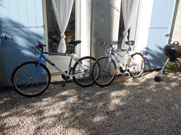 Dos bicicletas estacionadas frente a un edificio con camino de entrada de grava.