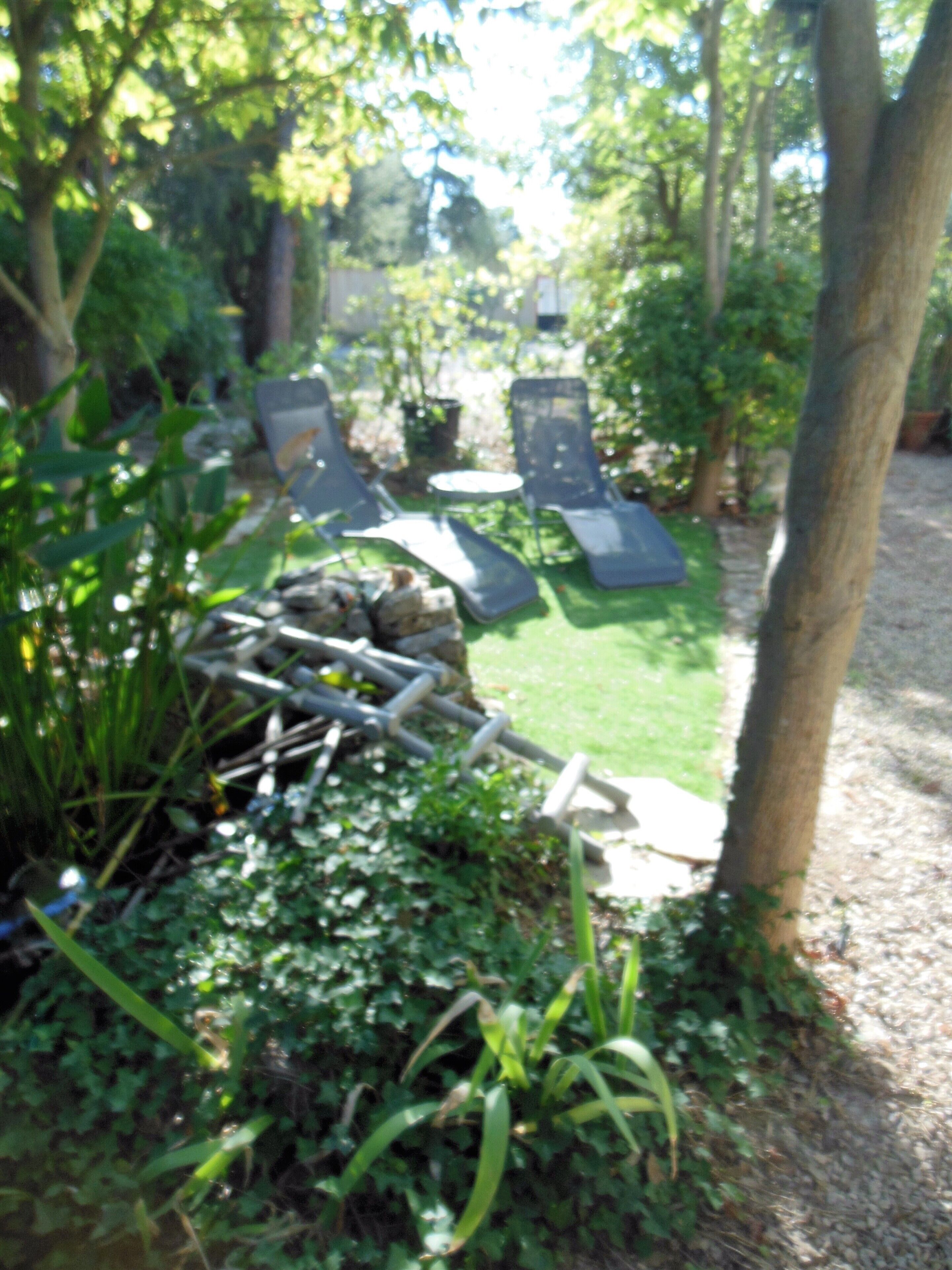 A garden area with a small table and two lounge chairs.