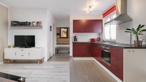 A modern kitchen with red cabinets, a built-in oven, and a large window. - Small holiday home in beautiful Dresden  (Dresden)