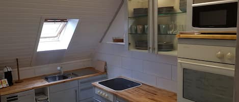 Eine Küche mit Dachfenster, Geschirrspüler, Mikrowelle und Herd.