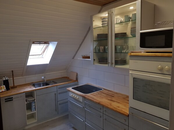 A kitchen with a skylight, a dishwasher, a microwave, and a stove.