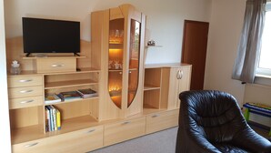 A room with a wooden entertainment unit, a black leather chair, and a television.