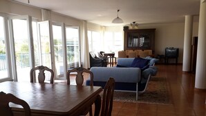 A spacious living area with a dining table and chairs, a sofa, and a cabinet.