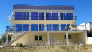 A multi-story building with balconies, a staircase, and a clear sky.