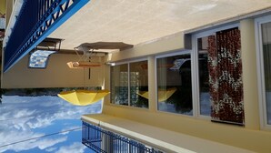 A building with a balcony, a blue railing, and a yellow awning.