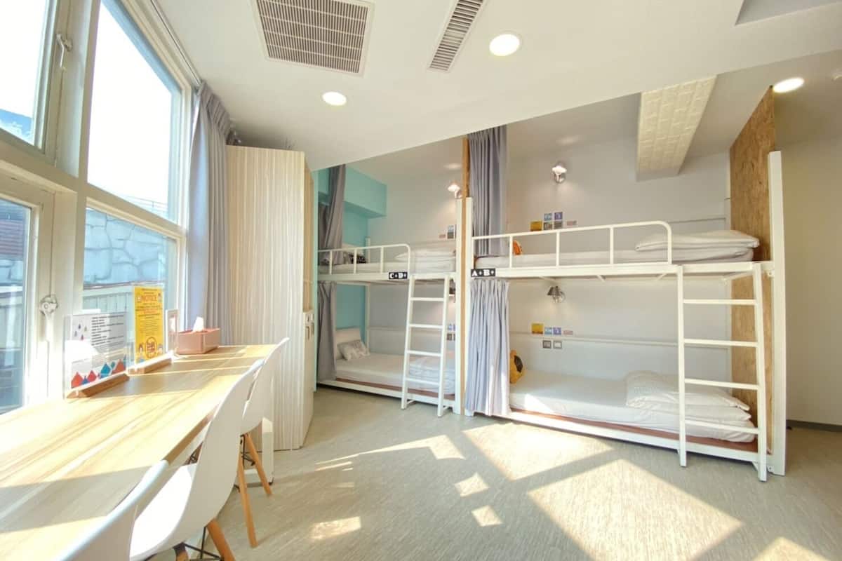 Ein Schlafsaalzimmer mit Etagenbetten, einem Schreibtisch und einem Stuhl.